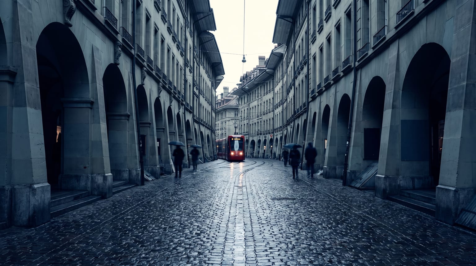 Berner Altstadtgasse mit Lauben an einem bedeckten Tag, eine rote Tramfront als einziger Farbakzent