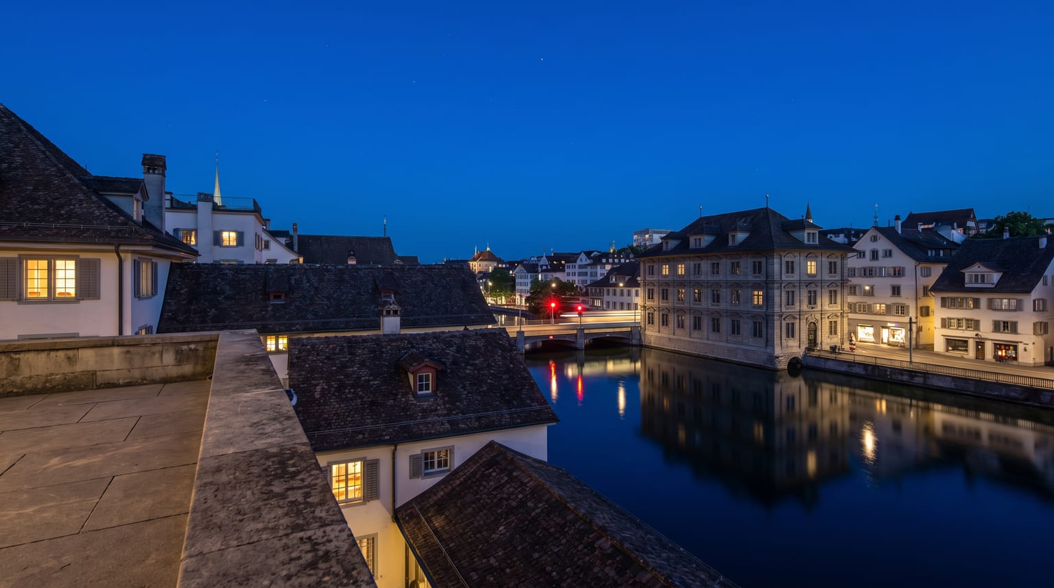 Zürcher Dächer zur blauen Stunde, Lichtreflexe im Fluss und ein einzelnes rotes Signallicht